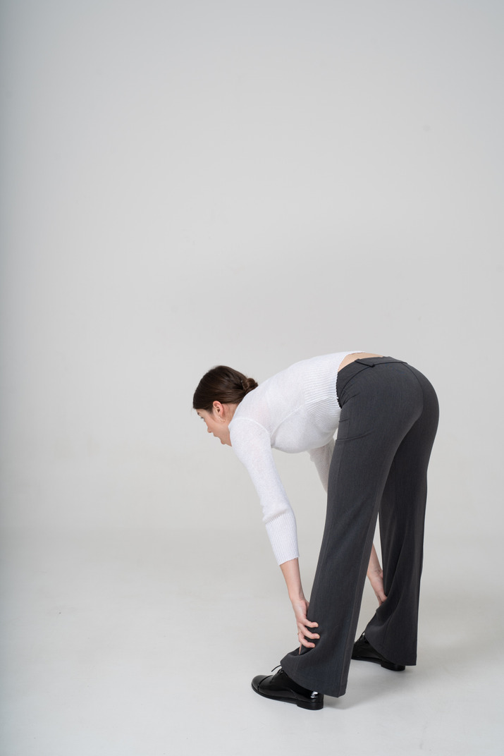 Side view of a young woman in suit bending down