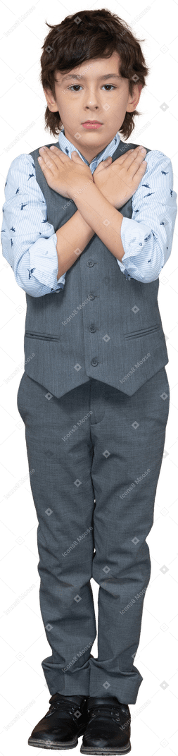 Vista frontal de un niño con traje gris de pie con las manos en los hombros