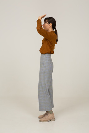 Side view of a young asian female in breeches and blouse raising hands