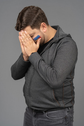 Three-quarter view of a withdrawn male football fan touching face