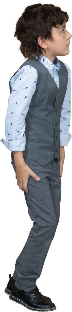 Vista lateral de un niño con traje parado
