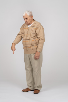 一位穿着休闲服的老人用手指向下指的正面图