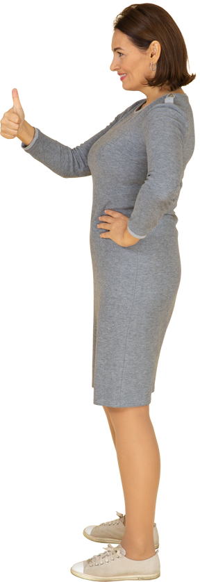 Vista laterale di una donna in abito grigio che mostra il pollice in su
