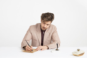 Красивый молодой человек держит ручку и пишет письмо