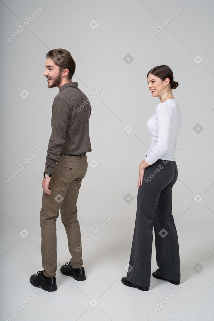 笑对年轻夫妇在办公室服装中的侧视图