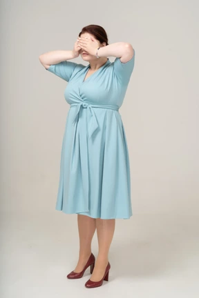 Side view of a woman in blue dress closing eyes with hands