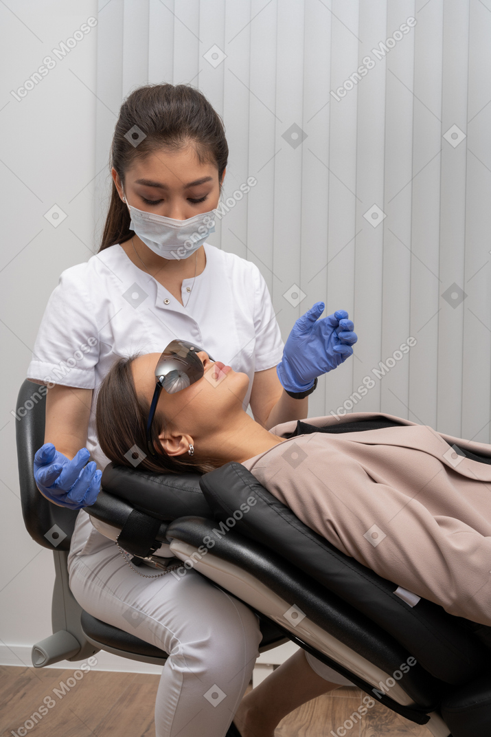 彼女の患者を調べるマスクとラテックス手袋の女性歯科医
