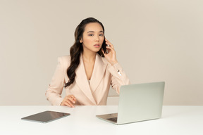 Empleado de oficina asiático involucrado en conversación telefónica