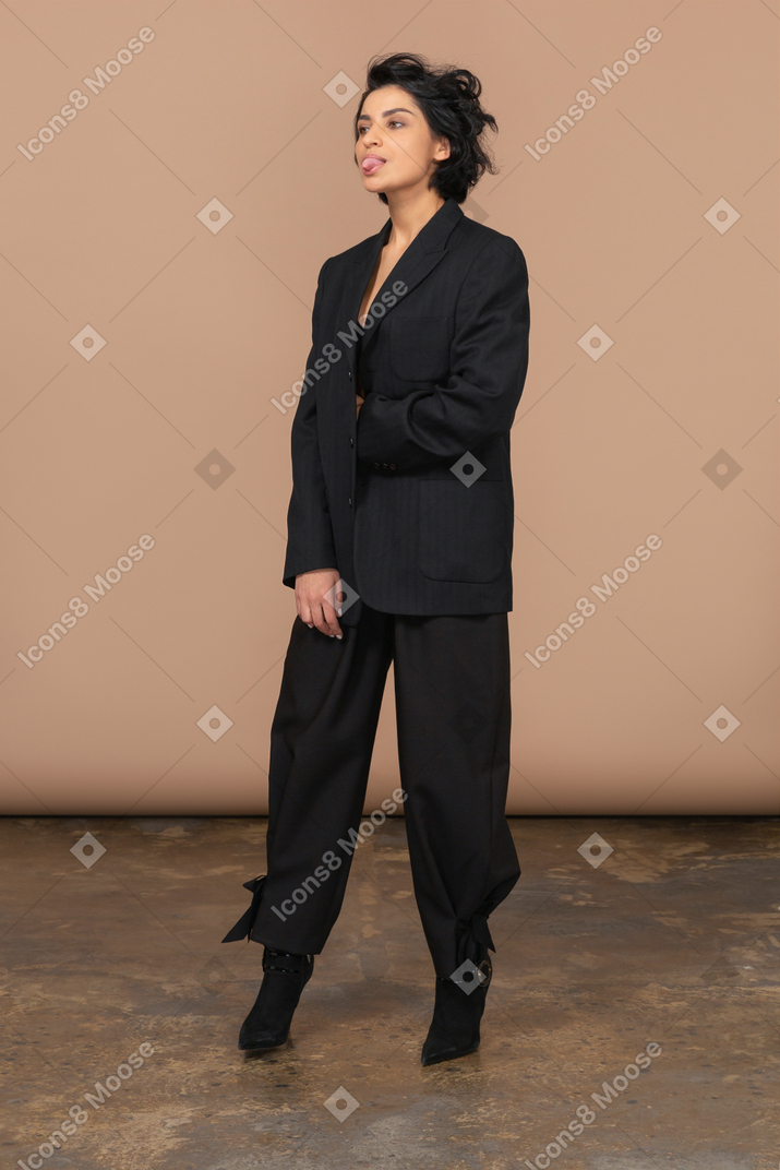 Vista de três quartos de uma mulher de negócios em um terno preto mostrando a língua
