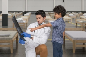 Médico y su pequeño paciente examinando una radiografía en un hospital improvisado
