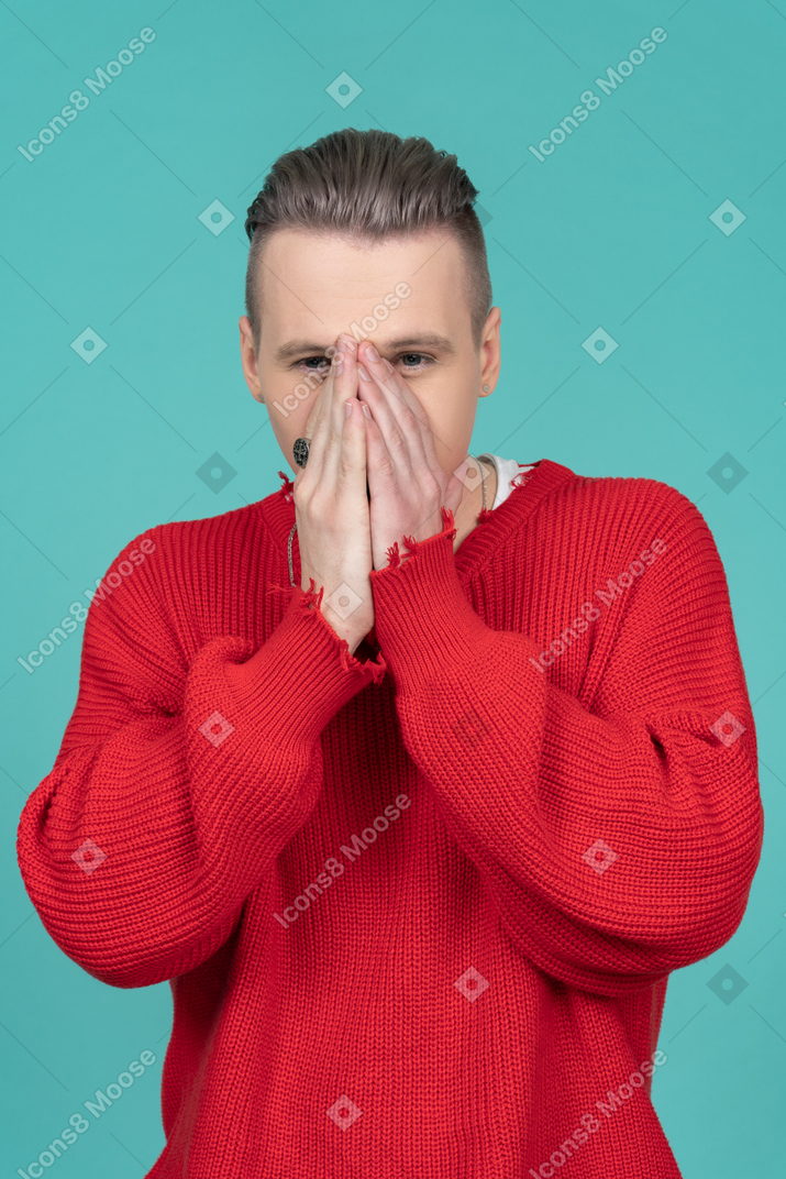 Young man covering face with both hands