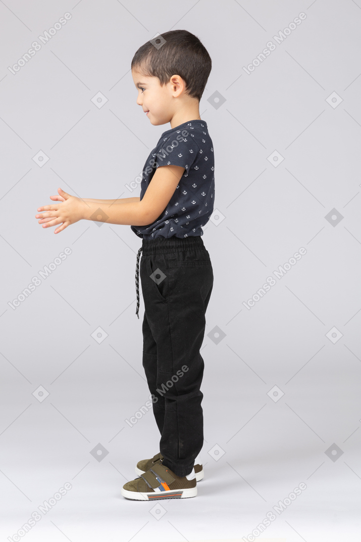 Side view of a cute boy posing with extended arms