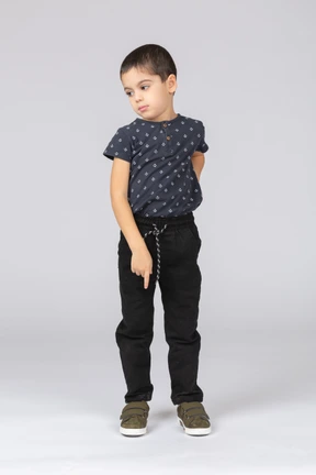 Front view of a cute boy pointing down with a finger