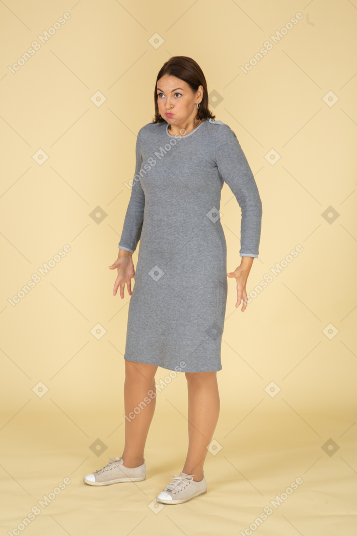 一个穿着灰色连衣裙的女人做鬼脸的前视图