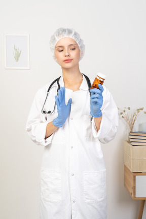 錠剤の瓶を保持している若い女性医師の正面図