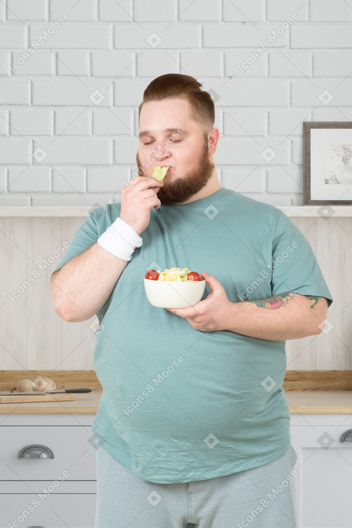 Man eating a salad in the kitchen