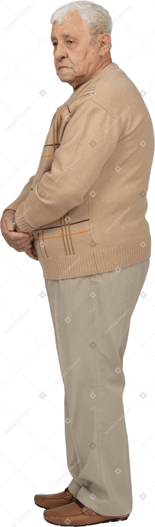 じっと立っているカジュアルな服装の老人の側面図