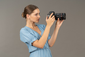 Side view of a young woman in blue dress taking shot