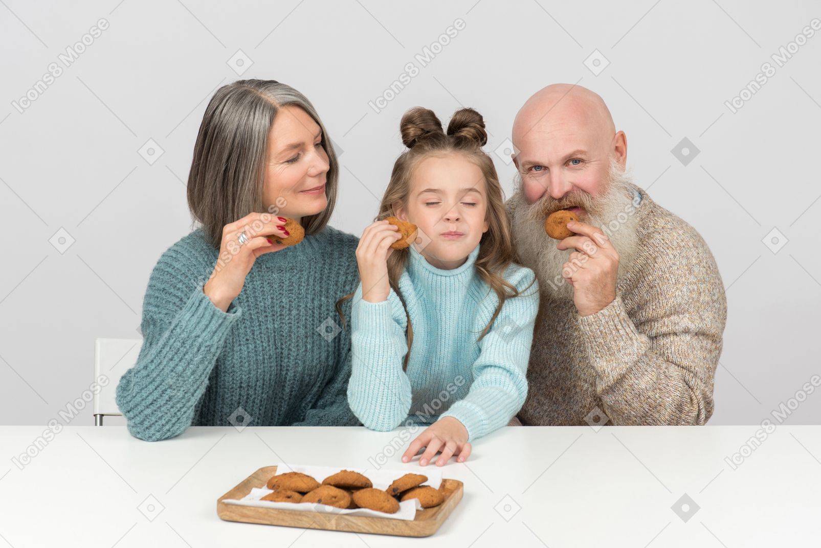 Grandparents and kid girl granddaughter eating cookies with eyes closed