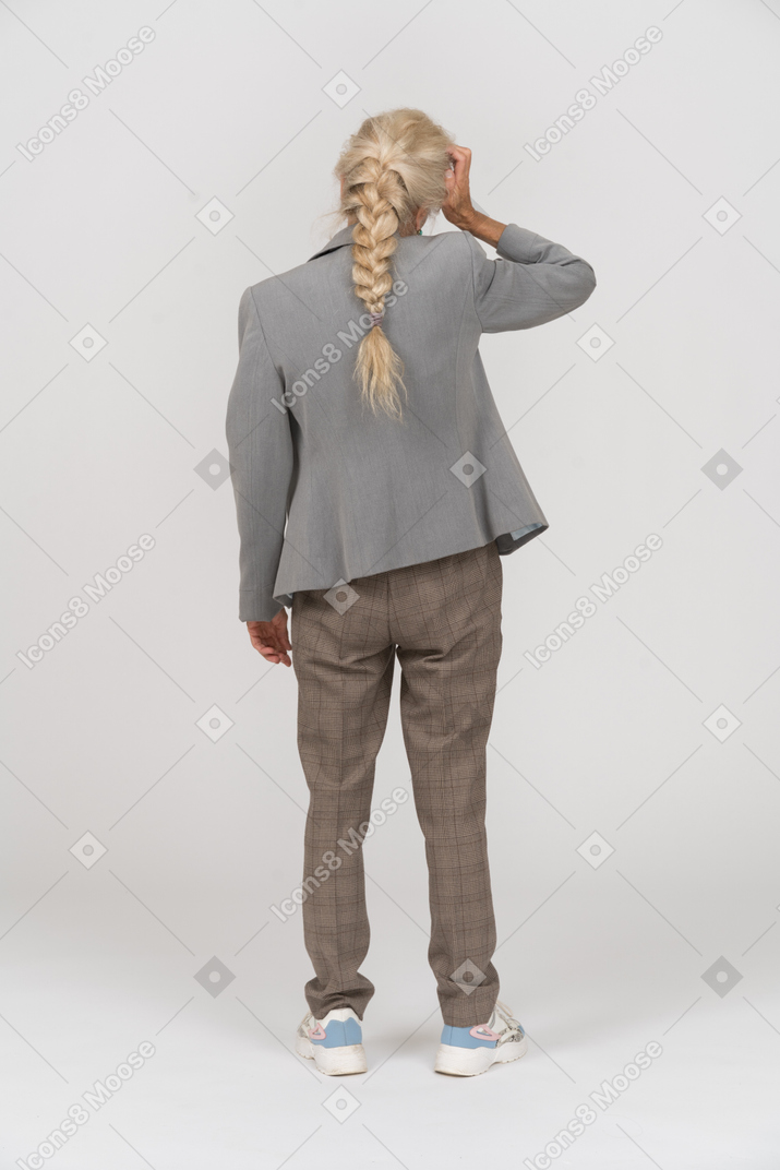 Vista posterior de una anciana en traje que sufre de dolor de cabeza