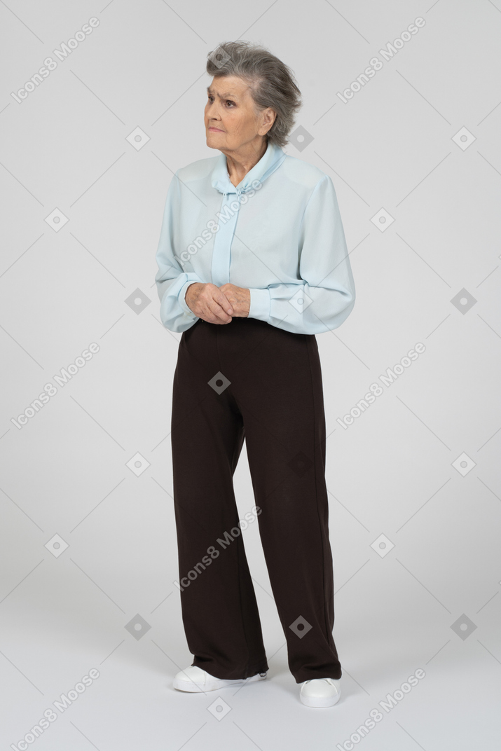 Vista frontal de una anciana que parece triste con las manos entrelazadas