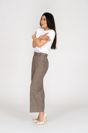 Vista di tre quarti di una giovane donna in calzoni e maglietta che si abbraccia