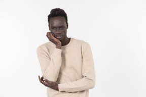 A young black man in a grey sweater standing alone on the white background