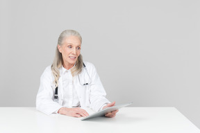 Aged female doctor working on a digital tablet