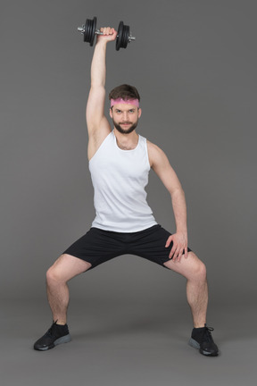 A young man squatting and lifting weights