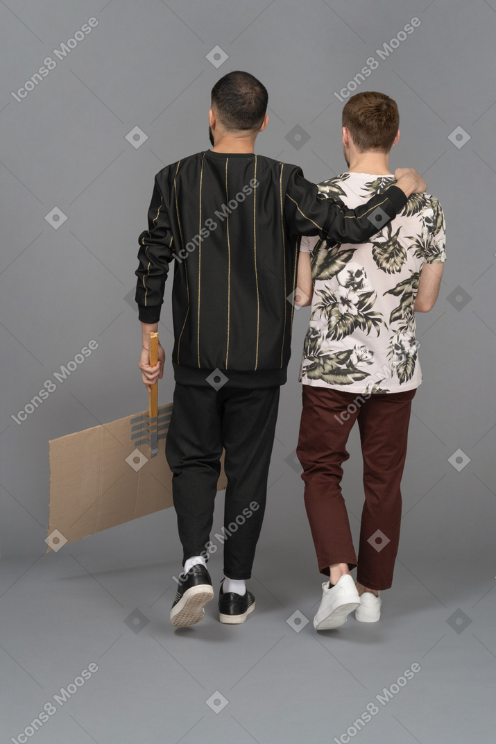 Back view of two young men with billboard half-hugging