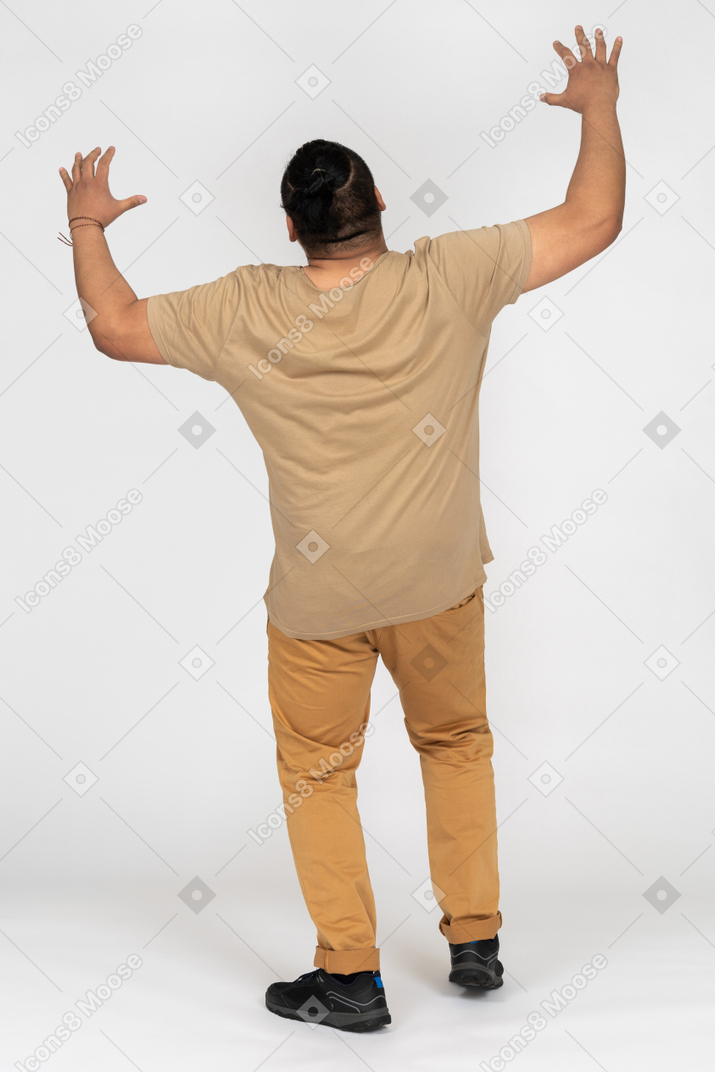 Man keeping hands up back to camera