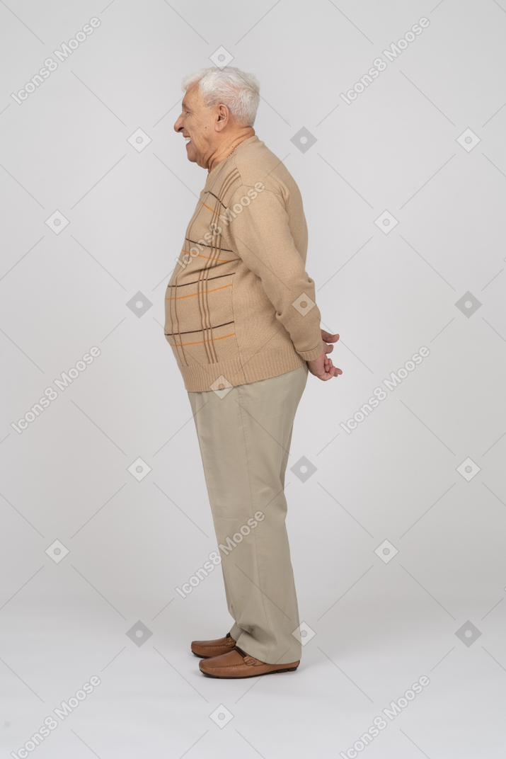 後ろ手で立っているカジュアルな服装の老人の側面図