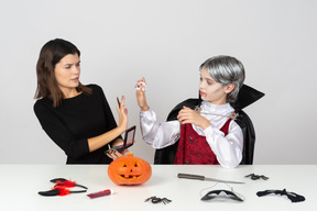 Menino em vampiro olhar mostrando dentes de vampiro falsos a mãe