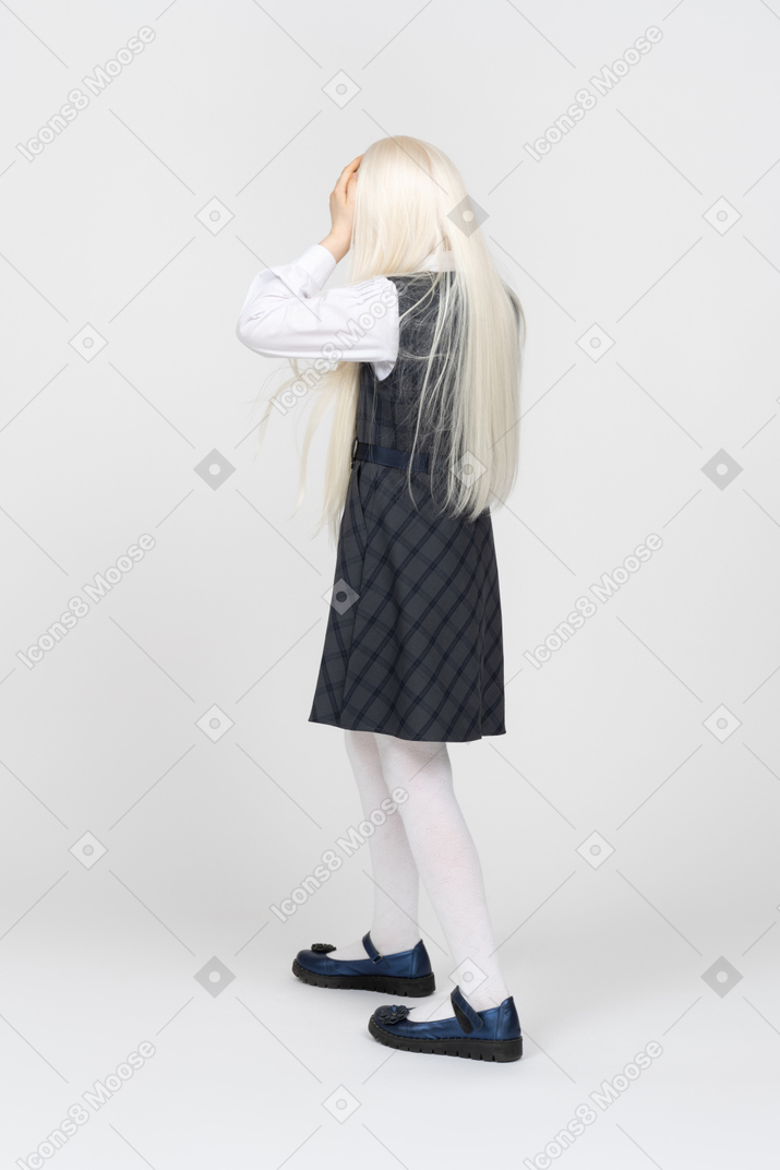 Back view of a schoolgirl touching her head