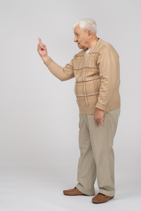 ロックジェスチャーを作るカジュアルな服装の老人の側面図