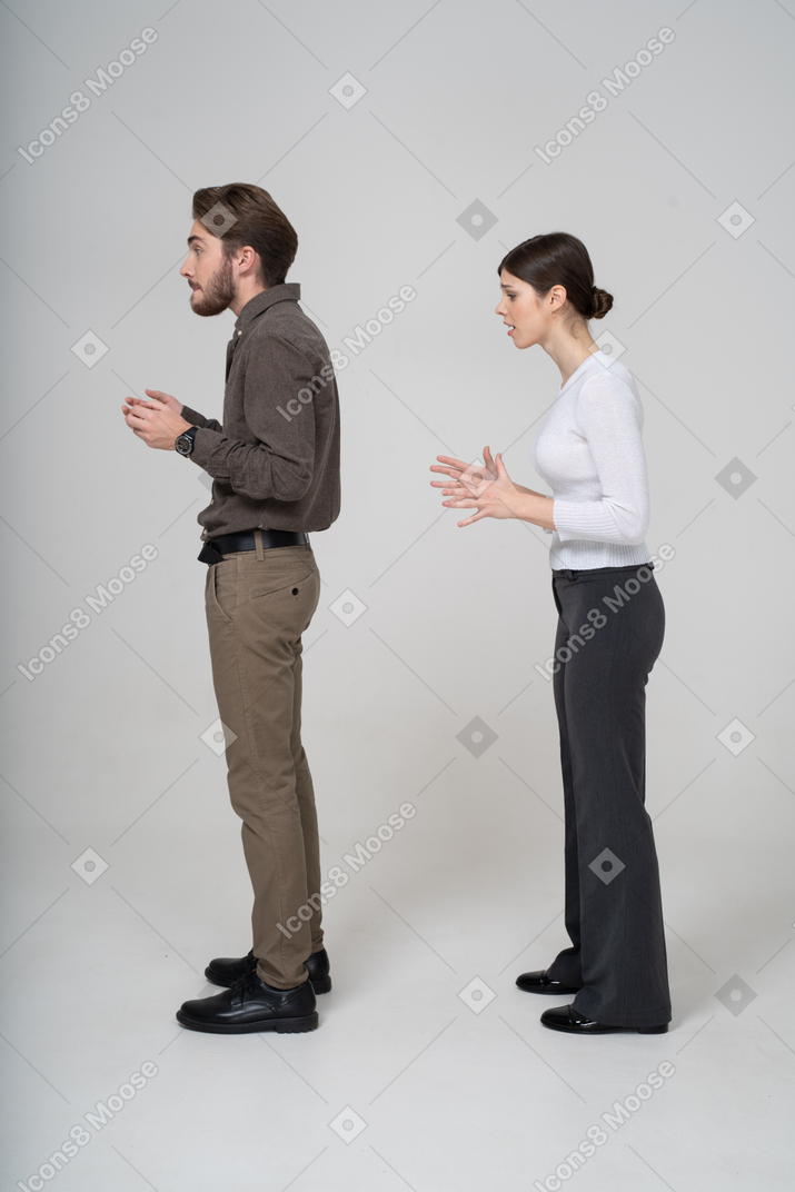 オフィス服で質問している若いカップルの側面図