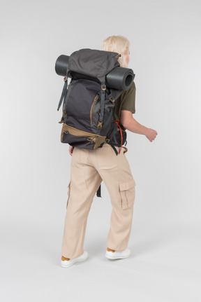 Female tourist with huge backpack standing back to camera