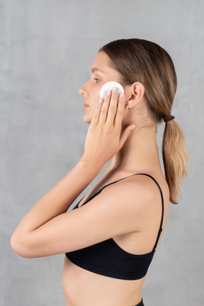 Side view of a young woman holding cotton pad