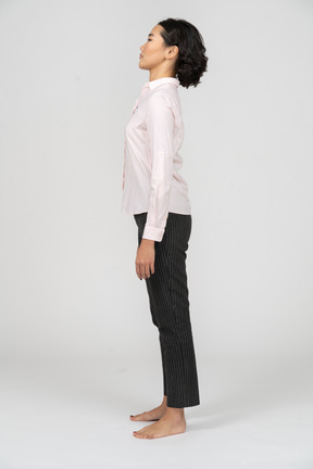 Vista lateral de una mujer en ropa de oficina de pie con los brazos a los lados