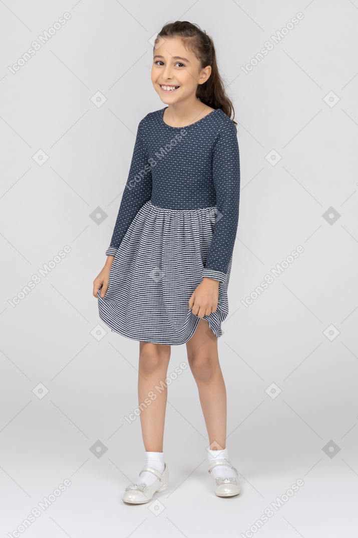 Front view of a girl holding the hem of her skirt with a wide smile