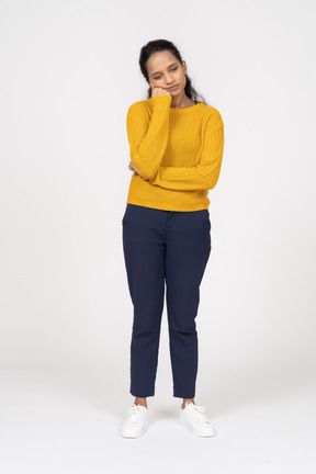 Front view of a tired girl in casual clothes holding fist on cheek