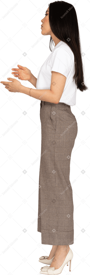 Side view of a gesticulating young lady in breeches and t-shirt explaining something