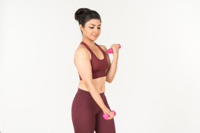 Young indian woman in sportswear lifting hand weights