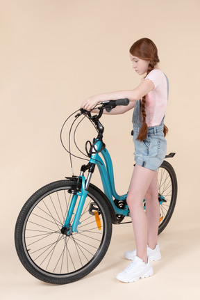 Teenage girl standing near blue bicycle