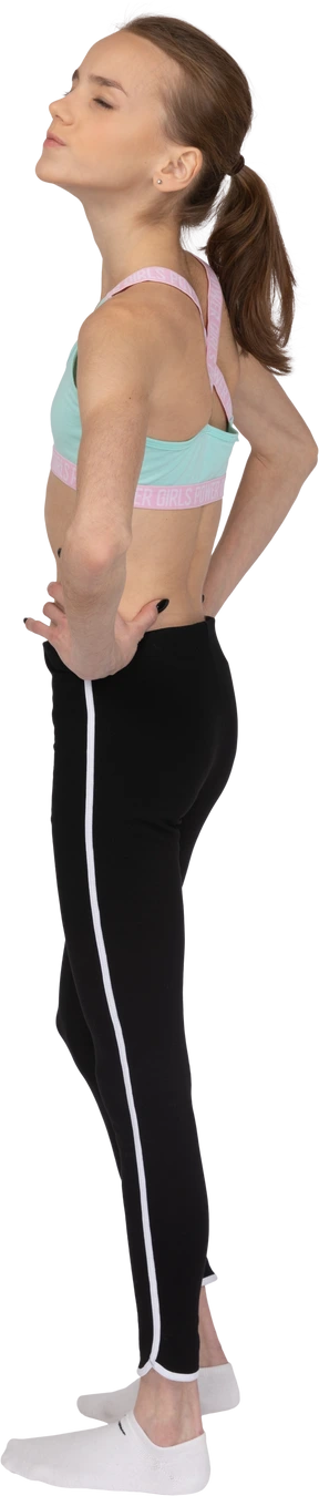 Three-quarter back view of a teen girl in sportswear putting hands on hips with her eyes closed