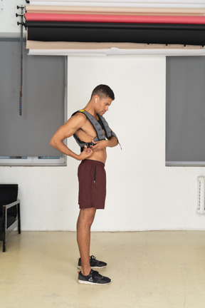 Side view of young man fitting weighted vest