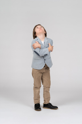 A young boy standing with his arms crossed