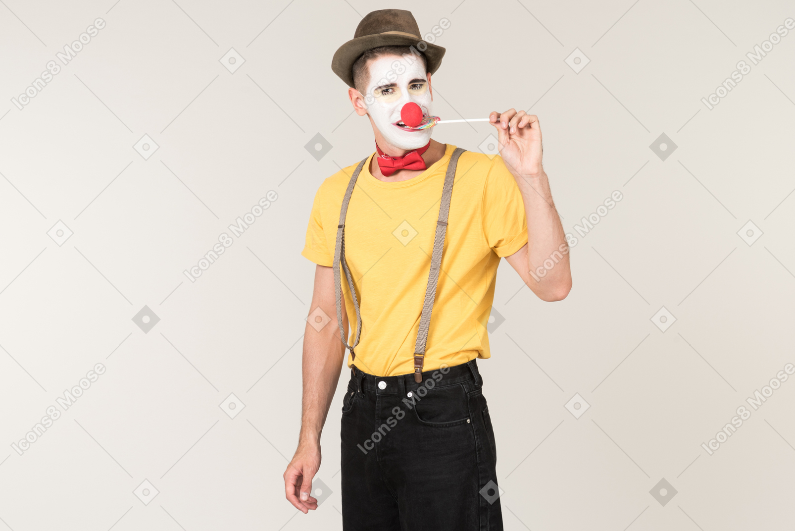 Male clown facing the camera and biting lollipop