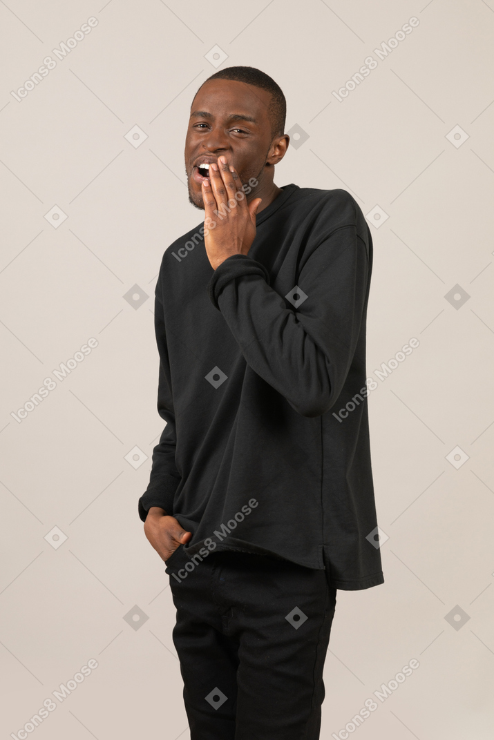Young man covering his mouth and talking