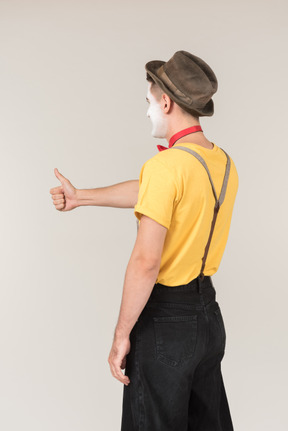 Male clown standing half sideways back to camera and showing thumb up